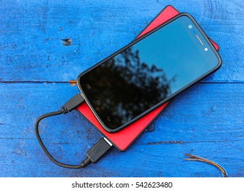 Smartphone And Powerbank On A Blue Board