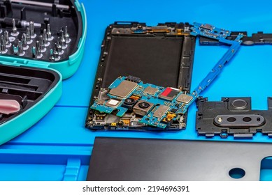 Smartphone Repair In A Service Center. Hands Of A Professional Master Repairman Repairing Disassembled Into Pieces Cell Phone. Internal Parts, Chips, Motherboards, Wiring, Fixing Process.