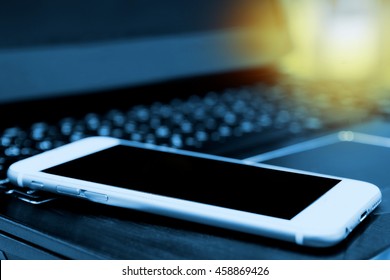 Smartphone screen with blur laptop for background  , copyspace , flare light