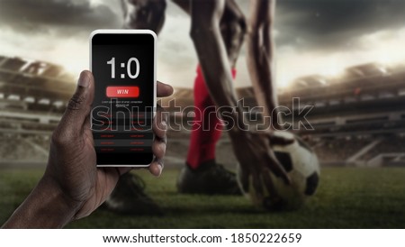 Smartphone screen with mobile app for betting and score. Device with match results on screen, sportsman on background during match. Gambling, betting, sport, finance, modern technologies concept. Stok fotoğraf © 