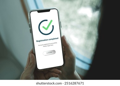 Smartphone screen shows Registration completed with Log in to proceed to the next step. The technological concept of project registration or membership application. - Powered by Shutterstock