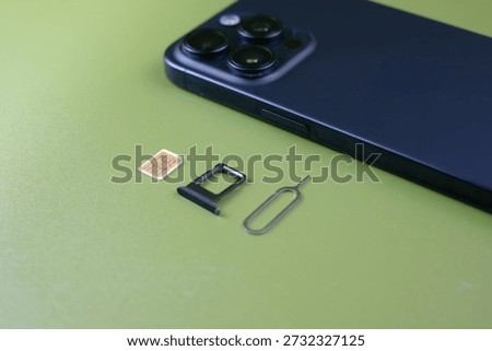 Smartphone with SIM tray and SIM eject tool on a green background with copy space