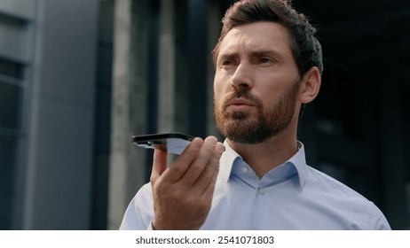 Smartphone talking microphone loudspeaker dictate to mic translation Caucasian businessman employer middle-aged man record audio message voice mail business male adult guy in city talk mobile phone - Powered by Shutterstock