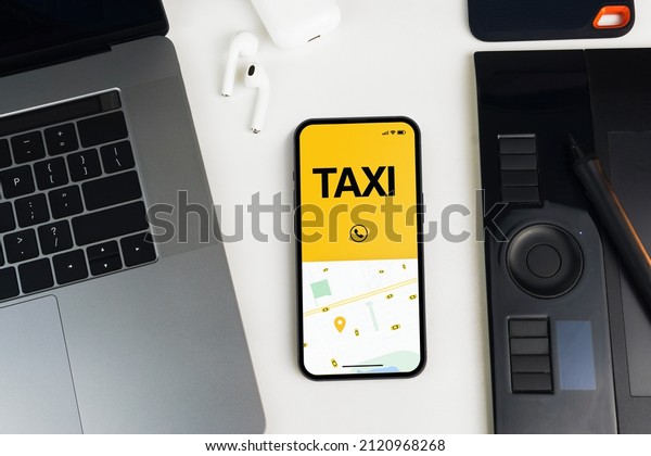Smartphone with Taxi Service app on the screen\
on white background table. Office environment. Mobility service\
provider worldwide.