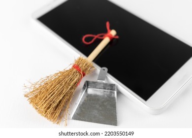 A smartphone and a toy cleaning tool. Image of smartphone cleanup - Shutterstock ID 2203550149