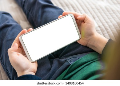 Smartphone With A White Screen In Hand Child. Smartphone With A Mock Up In The Hands Of A Child. Phone A For Mock Up Is Holding Kid. Top View Close Up