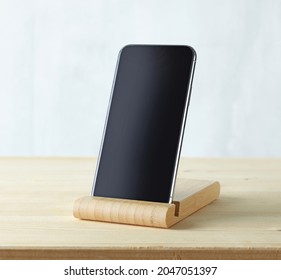 smartphone in wood stand on light wooden table