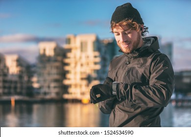 Smartwatch runner athlete man looking at his wearable technology smart watch on morning outdoor run checking his heart rate data running workout jogging through city streets. - Shutterstock ID 1524534590