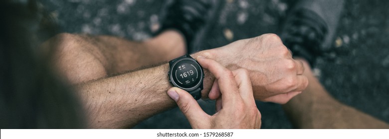Smartwatch smart wearable tech gadget for fitness health active lifestyle. Fit young man using new sports watch on jogging run checking his heart rate banner panorama.