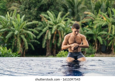 Smartwatch swimming sport man swim checking heart rate on smart watch. Male triathlete swimmer in a tropical hotel pool. - Powered by Shutterstock