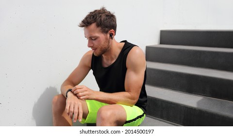 Smartwatch Using Man Connecting To Wireless Earphones To Listen To Music During Run Workout. Athlete Runner With Wearable Technology Sports Watch At Fitness Gym.