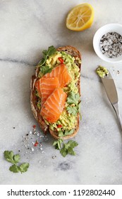 Smashed Avocado And Smoked Salmon On Rye Bread. Sandwich With Gravlax And Avocado Overhead Marble Table.