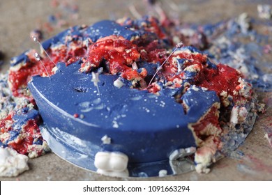 Smashed blue and red cake on concrete floor for first birthday. Messy pieces close-up side view