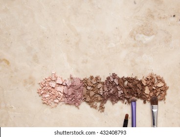 Smashed Eyeshadow Palette With Make Up Brushes On A Marble Counter Top Background