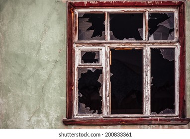 Smashed Glass Window With Old Wooden Frame On Grunge Wall Damaged House