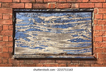 A Smashed Window Boarded Up With An Old Blue Wooden Board