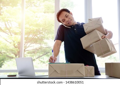 SME. Handsome Young Asian Delivery Man Happy After New Order From Customer And Lifting Many Packaging Parcel Box With Mobile Phone In Home Office, Small Business Owner, Cargo, Mail, Shipping Concept