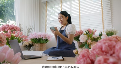 SME Owner Modern Small Flower Shop Work At Home Office Happy Smile Fist Up Read Text E-mail Message Banking Lending Money Online. Young Adult Woman Asia People Joy Seller Job In Sale Order Good News.