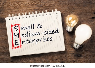 SME Or Small And Medium Sized Enterprises Text On Notebook With Two Different Light Bulbs