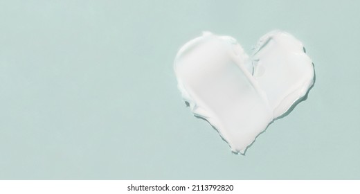 A smear of cosmetic cream in the shape of a heart on a blue background.