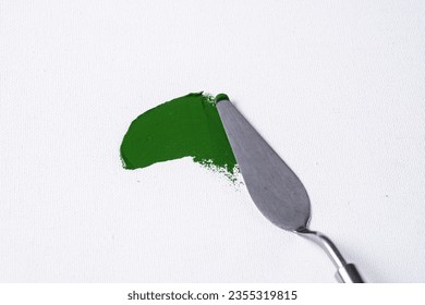 a smear of green paint, paint on canvas, palette knife with green paint.