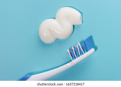 A Smear Of Toothpaste And Toothbrush On A Blue Background Top View.