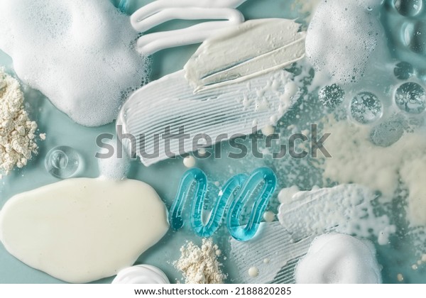 Smears of cream, serum,\
oil, powder. Drops transparent gel serum, cream, powder, oil on a\
blue background. Selective focus, smudge condition. Conception skin\
care.