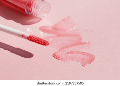 Smears Of Shining Lip Gloss And Lip Gloss Brush On Pink Background, Hard Shadows