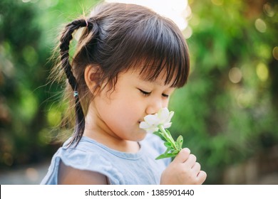 Smell Sensory Learning From Flower. Cute Asian Kid Exploring Natural Environment Through Outdoor Activity Like Play, Touch And See The Real Things Is The Best Method For Education In Children. 