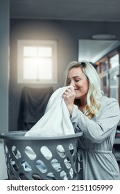 Smelling Oh So Fresh. Shot Of A Young Woman Smelling Fresh And Clean Laundry At Home.