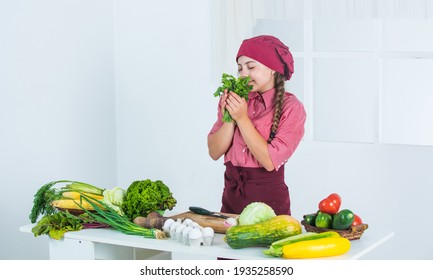 Smells Good. Teen Girl Smell Parsley. Fresh Raw Vegetables. Time To Eat. Happy Child Cooking In Kitchen. Healthy And Organic Food Only. Full Of Vitamins. Kid Wear Chef Uniform And Hat