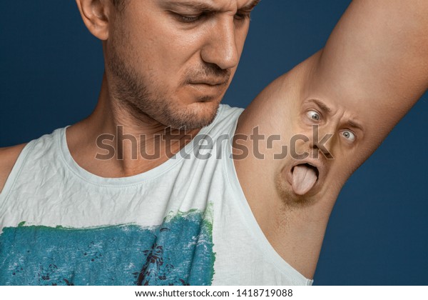 Smelly armpits in men. Concept of twisted panting\
face from bad smell