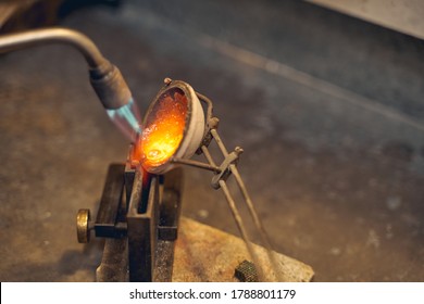 Smelted metal being poured by an experienced gold refiner from the crucible into a mold