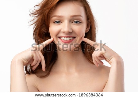 Smile. Beautiful Cheerful Red-Haired Young Lady Touching Dimples In Her Cheeks Smiling To Camera Posing Shirtless Over White Studio Background. Positive Emotions, Female Beauty Portrait Concept