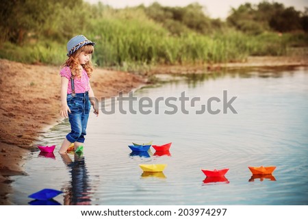 smile child playing with paper boats in a river