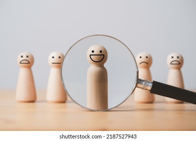 Smile face of wooden figure inside of magnifier glass among sad face for customer focus and relation management , excellent evaluation after client use product and service concept. - Shutterstock ID 2187527943