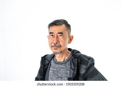 A Smile Of Happy Cool Asian Elder Man Faces In A Gray T-shirt And A Black Coat. Close-up Shoot On A White Background In The Studio. Positive Active Old Senior, And Healthy Concept.