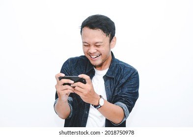 Smile And Happy Face Of Young Asian Man When Playing Game At Phone In Hand.