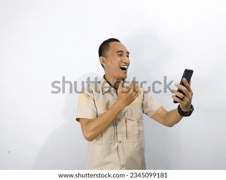 Smile, happy, sad, amazed face of Young Asian man when playing game at phone, video call, make a call. Holding a cell phone in hand. Using tan shirt isolated white background