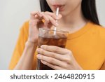 Smile happy thirsty asian young woman drinking or sip, holding glass of ice sparkling soda, cola water with straw, refreshness people, isolated on background. Temptation of food and beverage concept.