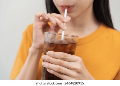 Smile happy thirsty asian young woman drinking or sip, holding glass of ice sparkling soda, cola water with straw, refreshness people, isolated on background. Temptation of food and beverage concept. - Powered by Shutterstock