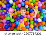 Smile kid lying colorful plastic balls pool. Colorful balls dry pool kindergarten playground child indoor play area. Playroom kids ball pit. Caucasian boy indoor playground kids play zone or kids zone