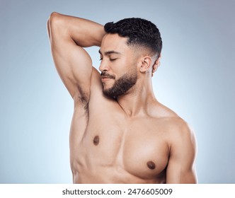 Smile, man and smelling armpit for hygiene with skin health and deodorant fragrance for self care in studio. Happy male person, underarm and check sweat for clean body and perfume by gray background - Powered by Shutterstock