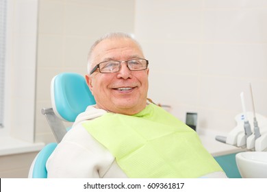 Smile Old Senior Man Sitting In A Dental Chair In A Dentist's Office.