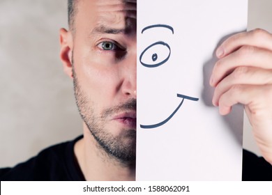 a smile painted on paper partially covers the face of a sad man, close up