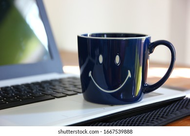 smile pattern on blue ceramic coffee cup on laptop