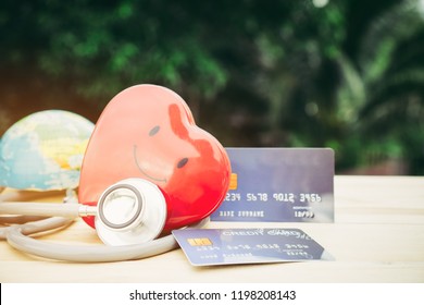 Smile Red Heart Stethoscope On Mock Up Credit Card With Cardholder In Hospital Wood Desk. Concept Of Health Insurance Cost Of Care, Self-care During Illness Using Payments Card For Medicals Service.