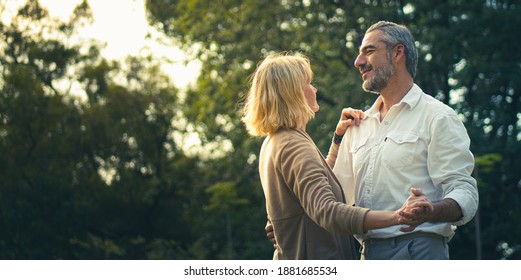 Smile Senior romantic couple dancing and looking each other feeling love and cherish on their anniversary in the park, happily senior citizen, well-managed retired life concept. Married lifestyle. - Powered by Shutterstock