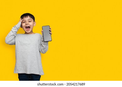 Smile And Shocked Little Boy Kid In Green Grey Shirt Blank Screen Of Mobile Phone On Yellow Background Copy Space