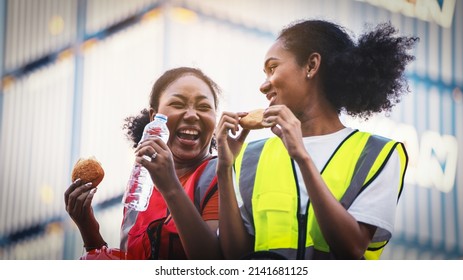 smile two African american woman foreman worker  or woman maintenance engineer in reflective vest safety jacket sits down on old truck relaxing, eats bread snacks and water during brunch break  - Powered by Shutterstock